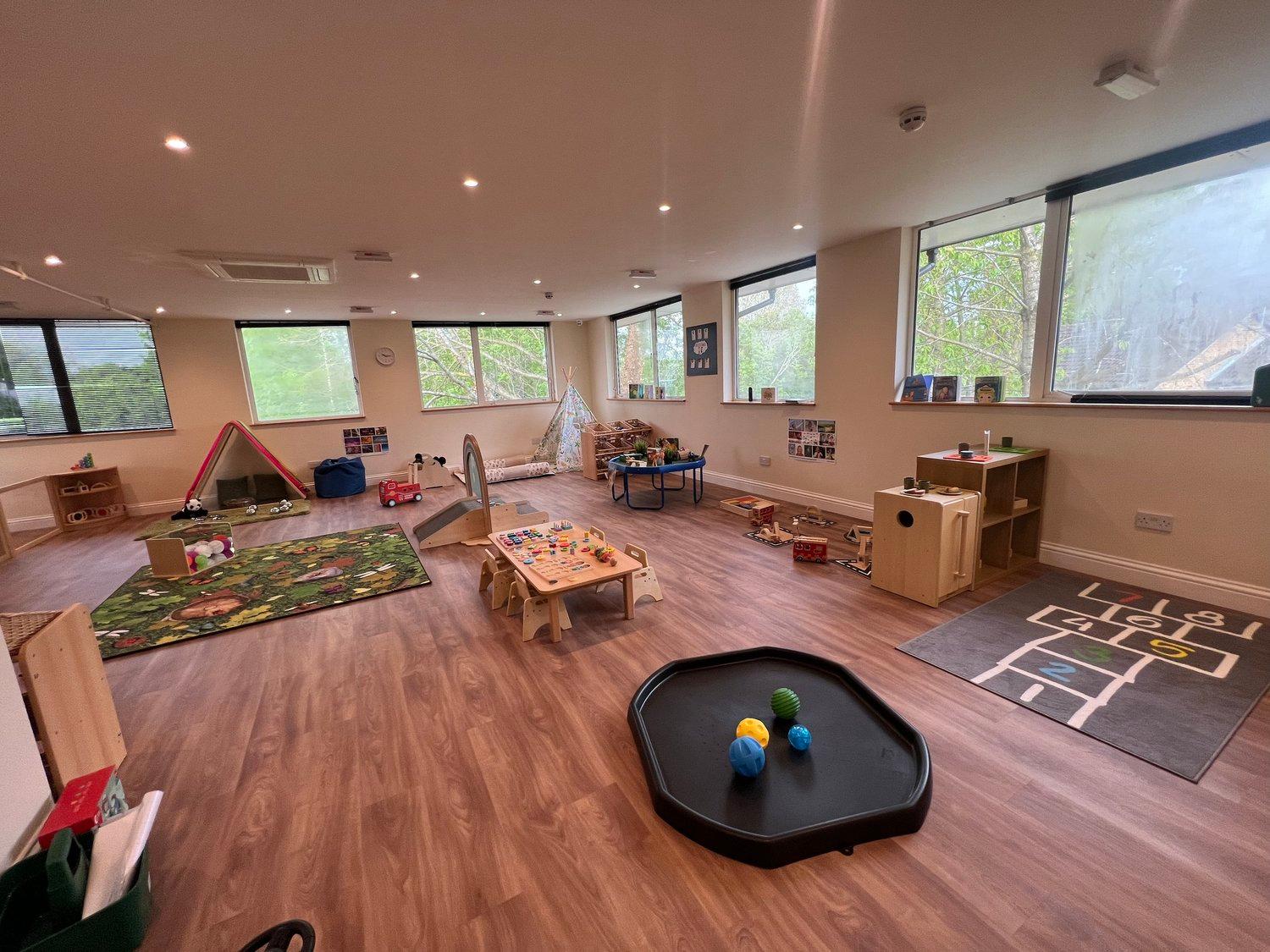 A bright toddler room with role play areas and open-ended resources