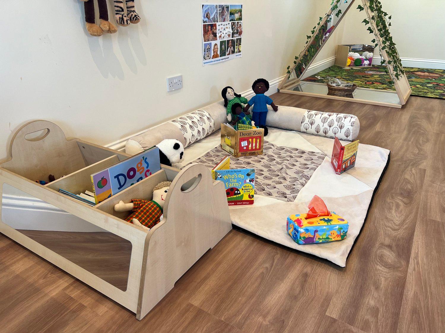A calm baby area with soft seating, books, and sensory toys