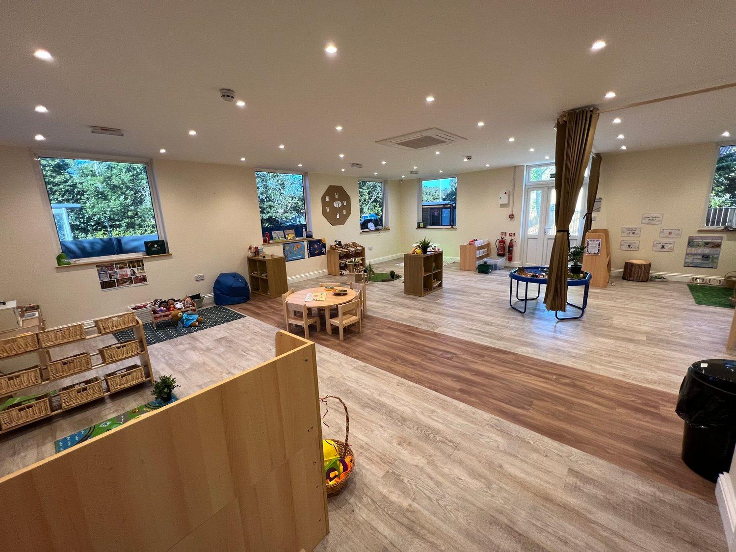 An inviting early years room with activity tables and open shelves