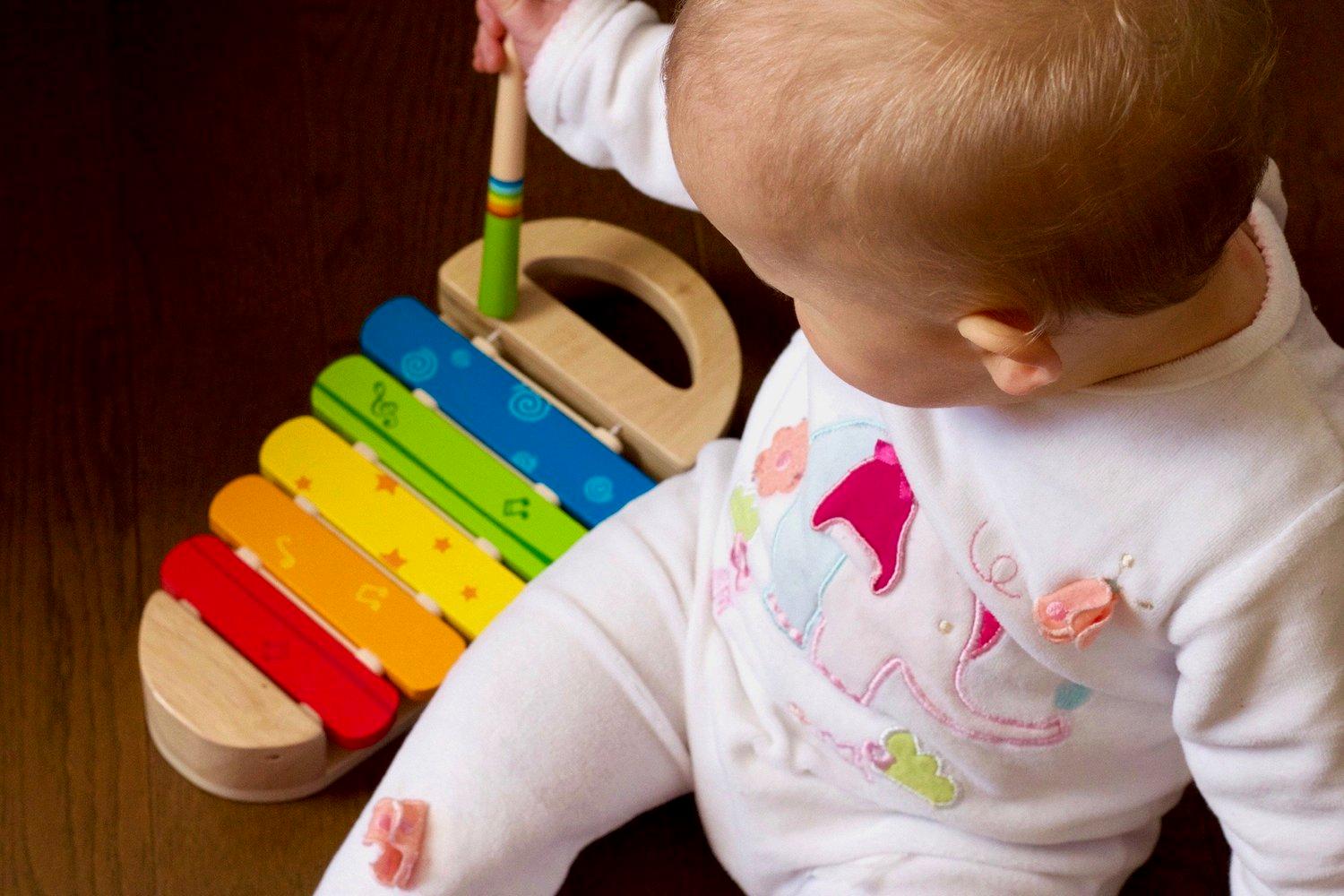 A baby exploring the sound and colour of a wooden xylophone